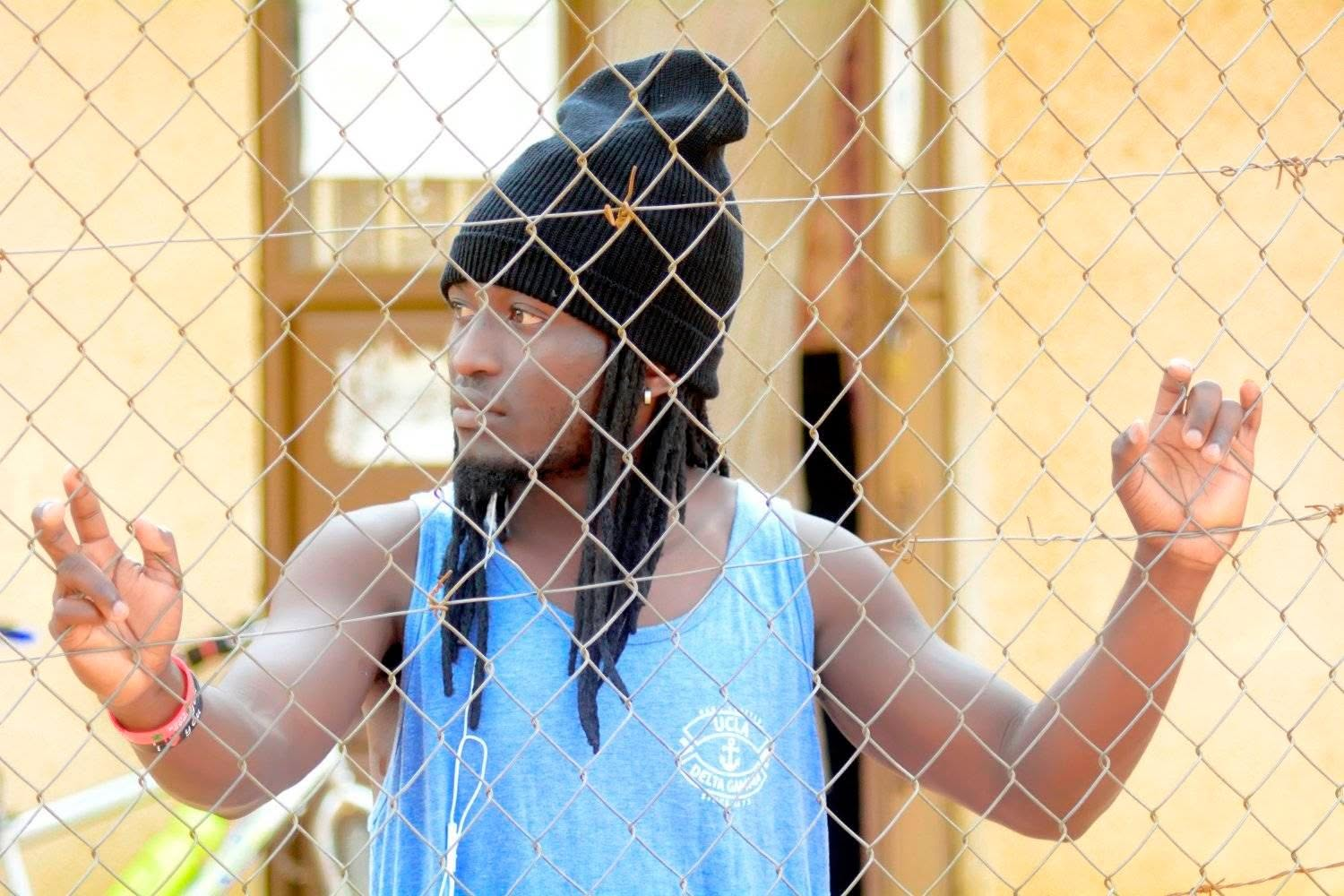 Eltou standing at a wire fence in the settlement