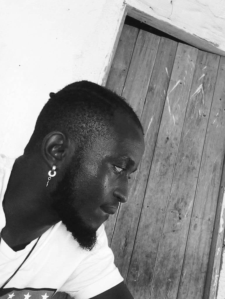 Eltou in profile beside a wooden door, in black and white