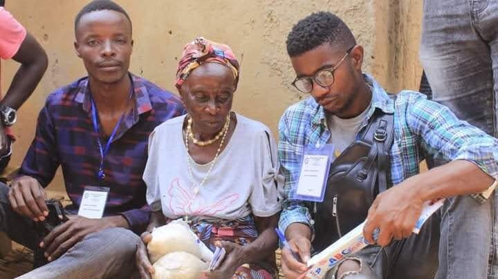 Two YRUD members sit with an elderly woman, registering her needs