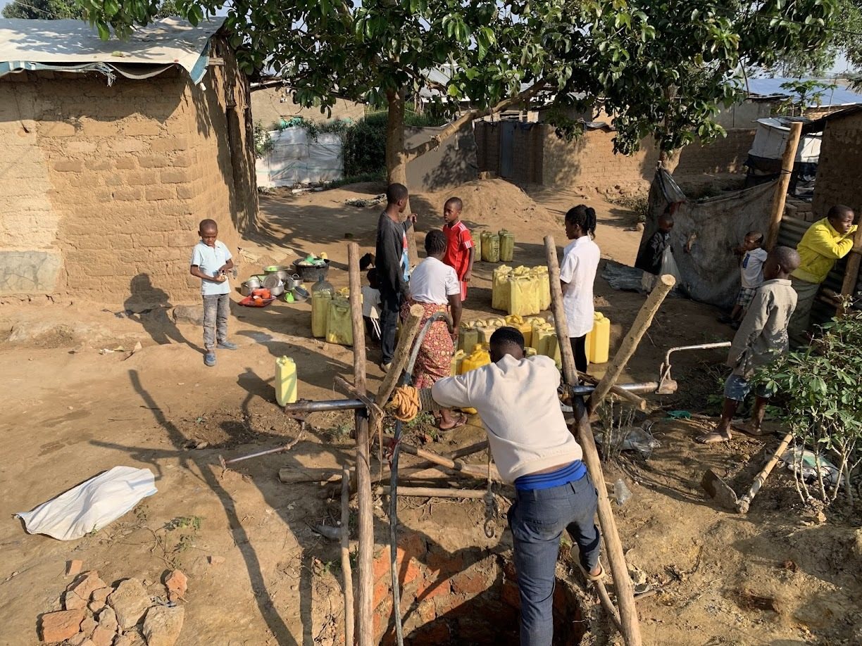 Community members drawing water at a borehole in the settlement
