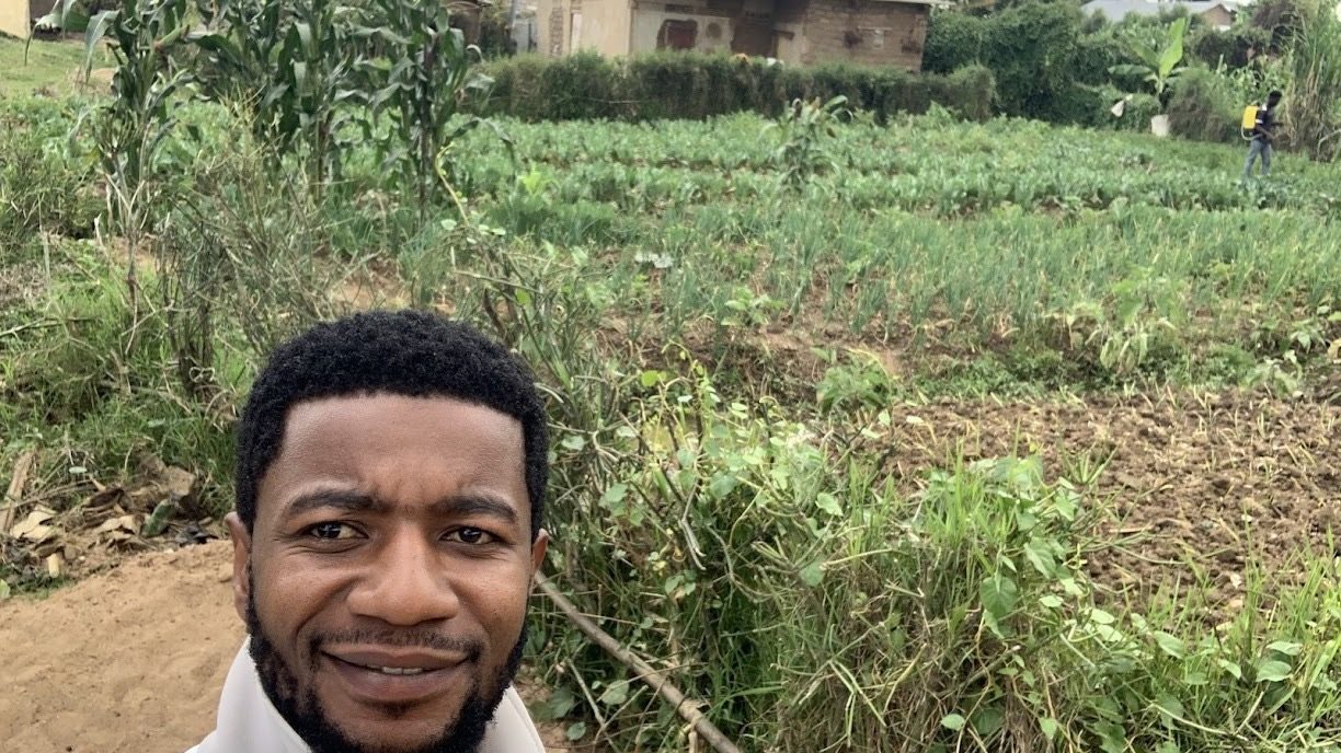 Justin Buma standing in a cultivated field at Nakivale