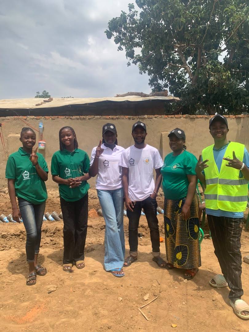 Six YRUD members standing together beside the planted beds after a day of planting